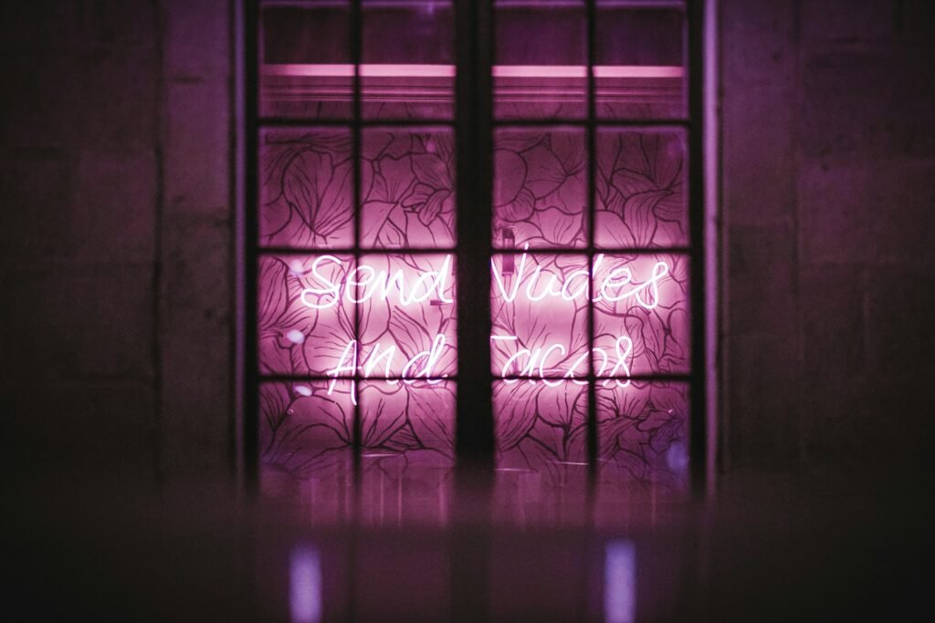 Bright pink neon lighting behind a decorative window frame adds an urban artistic touch.
